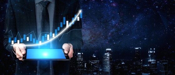 A businessman holds a digital tablet displaying a growth graph, set against a vibrant night...