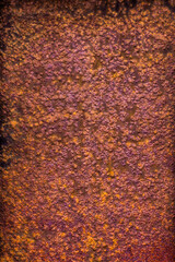 Metal surface with a thick layer of rust, exhibiting a predominantly purple hue with hints of orange and a rough texture