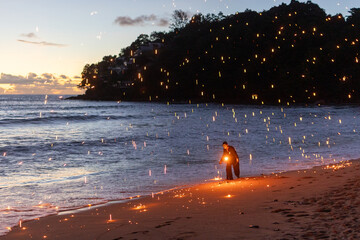 Fire performer lights up the beach, creating beautiful patterns against a sunset backdrop. 