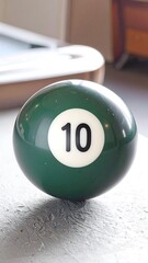 A close-up view of a billiard ball, displaying the number ten in a crisp white font against a deep emerald green surface.