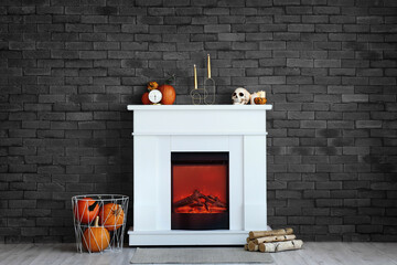 Modern fireplace with Halloween decor near brick wall