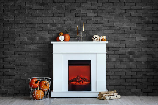 Modern fireplace with Halloween decor near brick wall