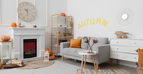 Interior of light living room with white fireplace, coffee table, cozy sofa and clock