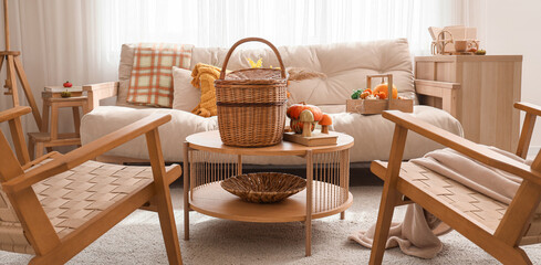 Interior of living room with autumn decor, sofa and armchairs