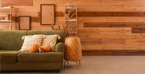 Green cozy sofa, pumpkins and lamp in autumn interior of living room