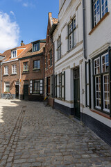 Historic street in Bruges’ old town with traditional buildings and bicycles parked along the cobblestone road on a sunny day.
