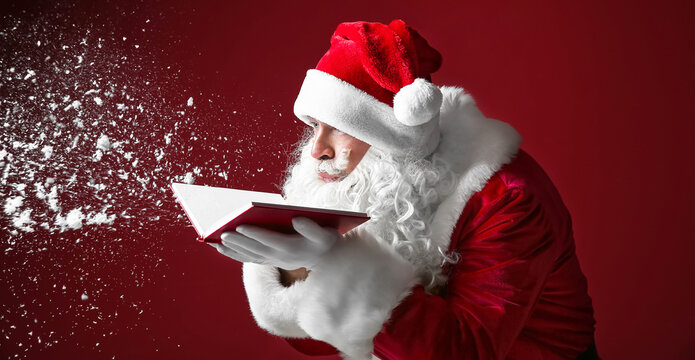 Portrait of Santa Claus with book blowing snow on color background