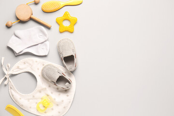 Stylish baby shoes with bib, socks, brushes and pacifier on grey background