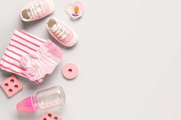 Stylish baby shoes with bottle of milk, clothes, pacifier and cubes on grey background