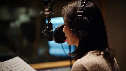 Medium shot of interpreter consulting bilingual script while speaking focusing on script lines with booth walls and equipment softly out of focus.