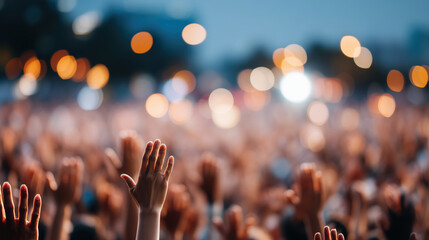 Crowd raising hands at concert with bokeh lights in background