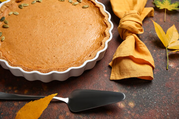 Baking dish with tasty pumpkin pie on brown background
