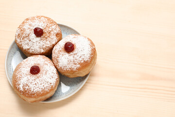 Plate with tasty donuts for Hanukkah celebration on wooden background