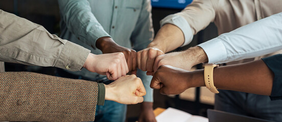 Teamwork, Power, Unity And Partnership Concept. Closeup sropped view of multucultural group of people making fist bump standing in circle. Workers doing fist pump together celebrating good deal