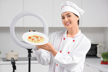 Female chef with tasty pasta recording cooking video class in kitchen