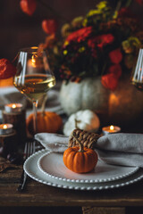 Cozy festive holiday table decor for home family Thanksgiving dinner. Traditional event, elegant natural decoration. Wooden rustic table, countryside style. Burning candles, floral centrepiece pumpkin