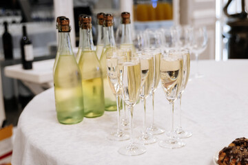 Glasses of chilled sparkling wine and bottles on elegant white table at celebration event