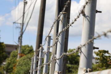 有刺鉄線とフェンスのクローズアップ。防犯や境界を示す概念。