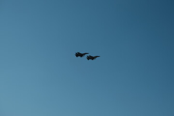 Pair of F-16 fighter jets flying together in close formation against clear blue sky, representing air force strength, defense aviation, and advanced military aircraft technology.