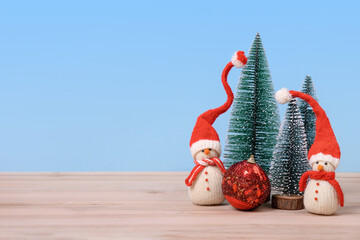Christmas background with knitted snowmen in red hats and Christmas trees with red ball and space for text, greetings, promotions, and discounts. Christmas and New Year card.