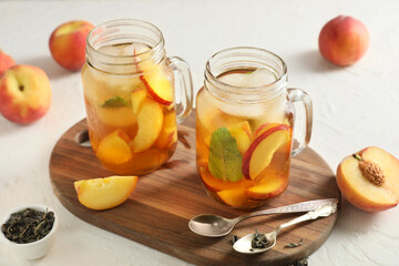 Wooden tray and glasses of tasty peach iced tea on white grunge background, closeup