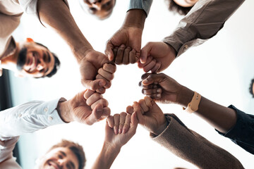 Obraz na płótnie Canvas Teamwork, Power And Partnership Concept. Below view of multucultural group of smiling people making fist bump standing in circle. Workers doing fist pump together celebrating good deal