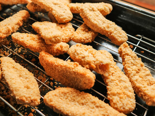 A rack of chicken goujons are on a metal cooking tray. The nuggets are golden brown and crispy. Simple tasty family meal. Cooking meat. concept