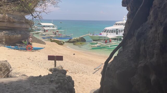 Tropical beach of Apo Island in the Philippines with anchored dive boats and a swimmer enjoying the turquoise water. A diving hotspot in Southeast Asia.