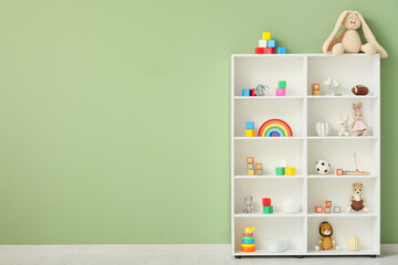 Shelf unit with children's toys near green wall