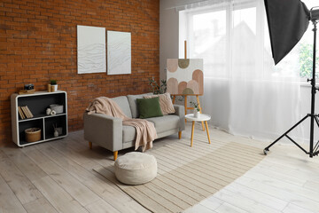 Photo shoot of living room with sofa, easel and paintings in studio