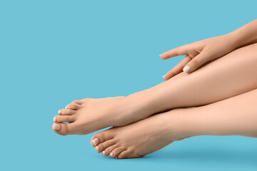 Fototapeta premium Feet of young woman with fresh pedicure on blue background, closeup