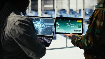 Close up of army general and coworker in data center integrating AI into radar systems for missile tracking. Teamworking soldier and technician in server hub analyzing aerial movement on device