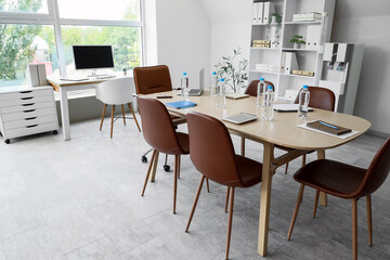Interior of conference hall with desks, shelf unit and water cooler