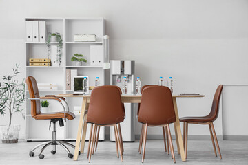 Interior of conference hall with table, shelf unit and water cooler