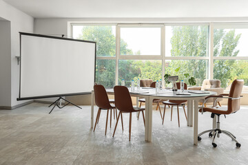 Interior of conference hall with desk, armchairs and projector screen