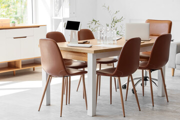 Table with laptop and tablet computer prepared for business meeting in conference hall