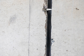 electrical cable is laid in protective corrugation in groove in wall. Protruding electric