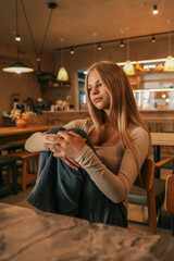 Young woman sitting in cozy café with warm lights, thoughtful mood, casual style and relaxed atmosphere indoors