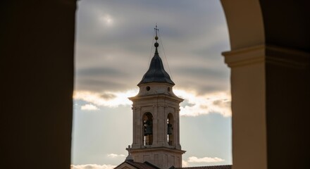 Historic bell tower framed by arch at sunset