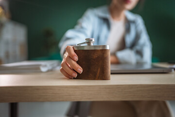 Businesswoman placing hip flask on desk during work