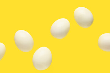 Flying many boiled chicken eggs on yellow background