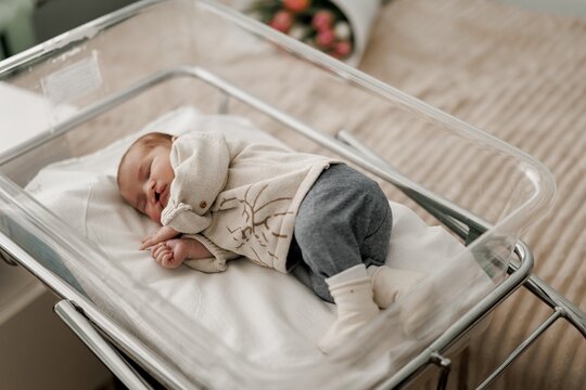 A sleeping newborn baby with congenital defect of cleft lip and palate wrapped in a cozy blanket, resting peacefully in a crib. The baby has a serene expression
