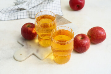 Glasses of fresh apple cider and fruits on white background, closeup