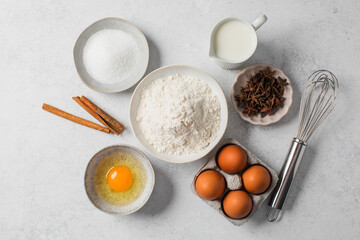 Baking ingredients flat lay with flour, eggs, sugar, and spices on marble surface