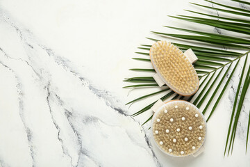 Body massage brushes and palm leaf on white background