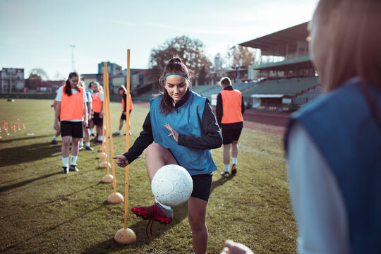 Young woman practicing soccer drills with teammates on field
