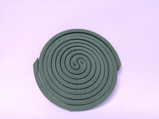 Fototapeta premium A green mosquito coil in a spiral shape placed on a plain white background.