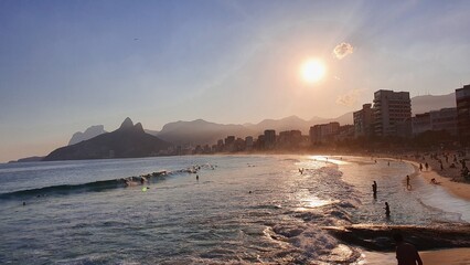 Sunset at Ipanema Beach with Dois Irmãos mountain and city skyline.