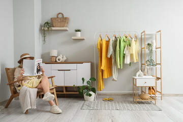 Young woman reading magazine on armchair in dressing room