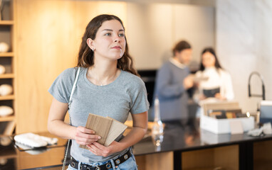 Female buyer with samples of material chooses kitchen set in a furniture store